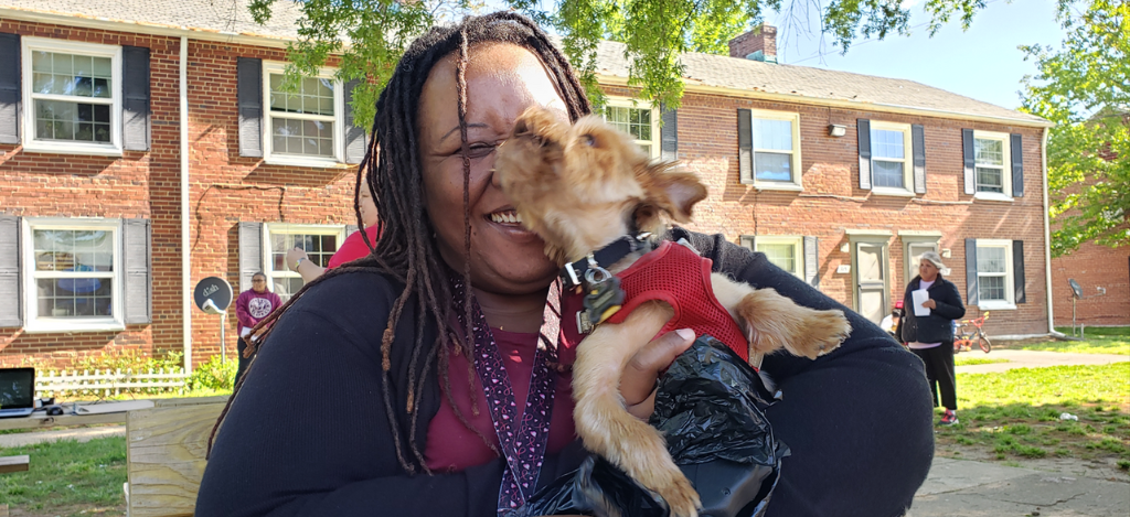 Woman laughing with her small light brown dog, featured in Community Pet Pantry